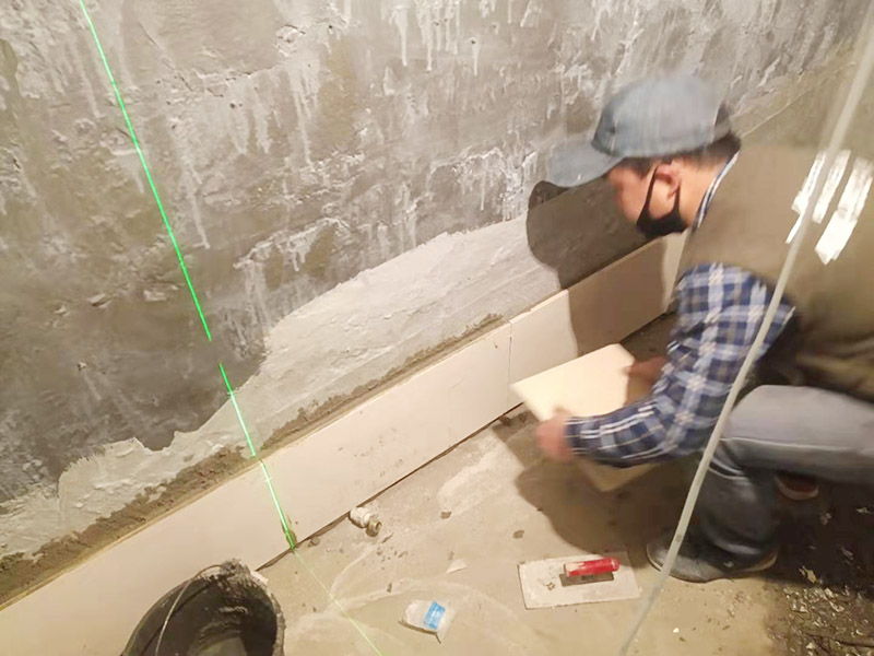 衛(wèi)生間墻面貼磚：施工前將需要的材料整齊堆放在一旁待用。首先應(yīng)除去基層表面的污垢，油漬，浮灰;除去基層上所有涂料層，膩?zhàn)訉?如果基層未能達(dá)到平整度要求，需對(duì)基層進(jìn)行預(yù)先的找平處理。 鋪貼瓷磚前需事先找好垂直線，以此為基準(zhǔn)鋪貼的瓷磚高低均勻、垂直美觀;此外，施工前在墻體四周需彈出標(biāo)高控制線，在地面彈出十字線，以控制地磚分隔尺寸。 加水后將粘結(jié)劑漿料攪拌至潤(rùn)滑均勻，無明顯塊狀或糊狀結(jié)塊，攪拌后的漿料靜置5-10分鐘后再稍加攪拌1-2分鐘即可使用。在開始鋪貼施工前，需要先清理瓷磚表面的浮灰，污垢等。將調(diào)制好的漿料均勻地抹在瓷磚背面，要求漿料飽滿。將瓷磚平整地鋪貼在基層上，使用橡膠錘將瓷磚拍實(shí)鋪平。施工過程中，可小幅度轉(zhuǎn)動(dòng)瓷磚，使?jié){料與瓷磚背面充分接觸。